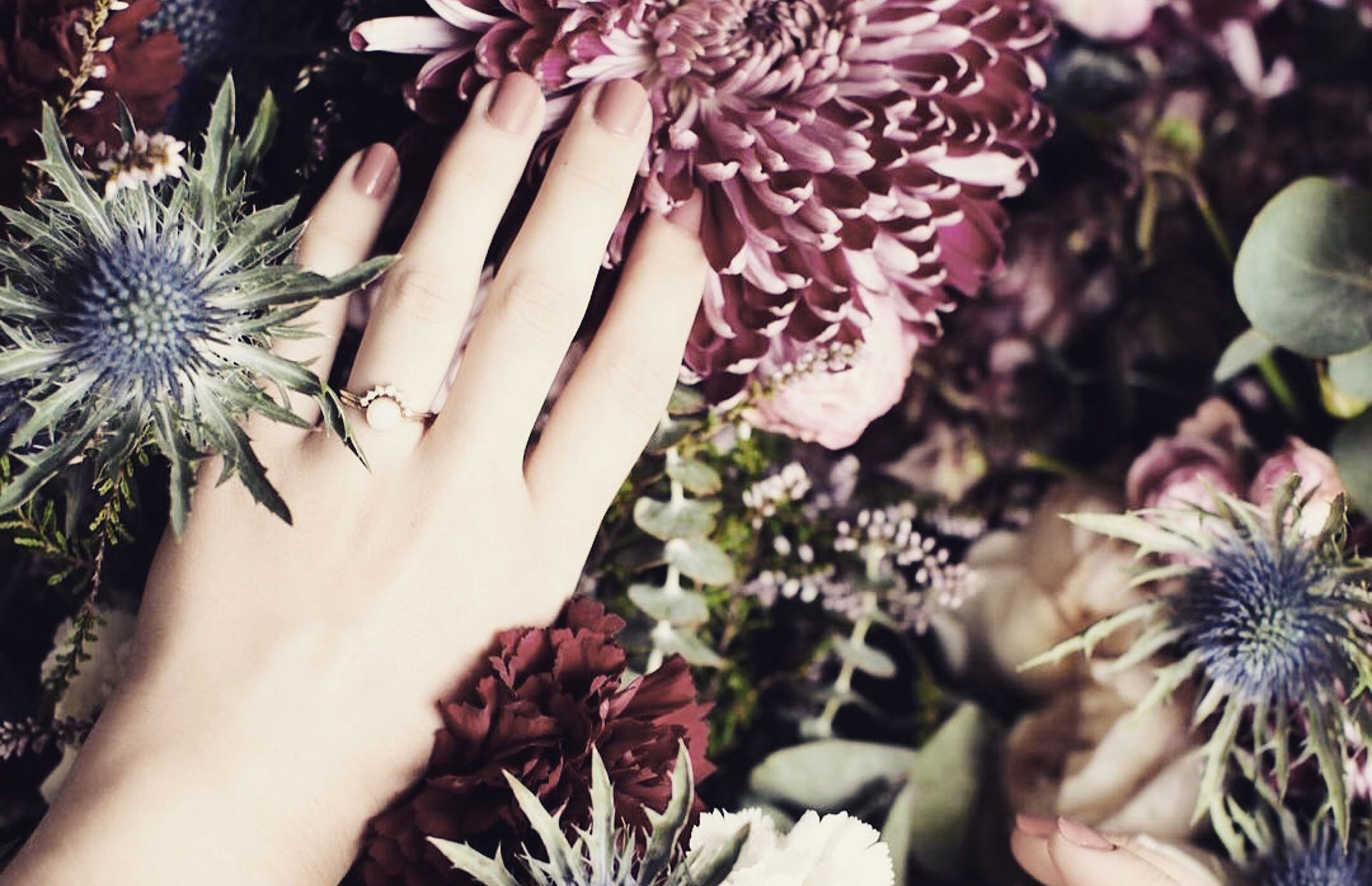 Main de femme avec bague de mariage sur un lit de fleurs